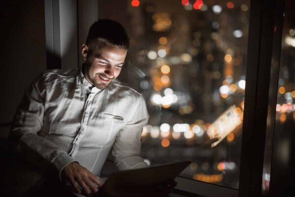 Smiling Young Man Looking at His Laptop