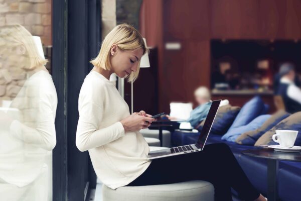 Woman in White with A Phone on Hand and A Laptop on the Lap