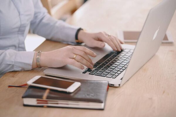 Woman Working on A Laptop with Phone and Notebook on the Table
