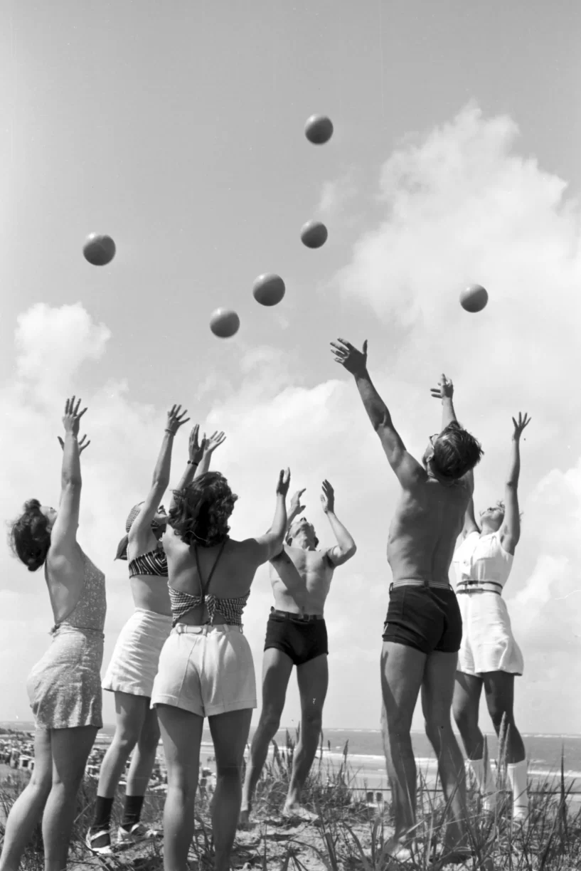 Group of Men and Women At The Beach Throwing Balls in The Air