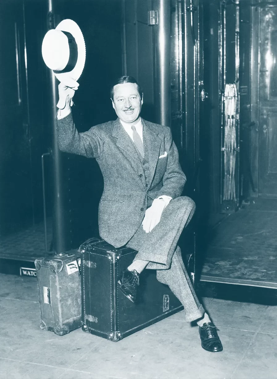 Man Sitting on A Suitcase Raising His Hat