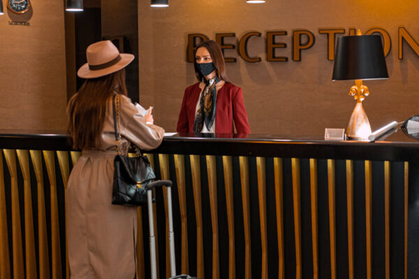 Lady with a hat facing a lady receptionist in the reception counter.