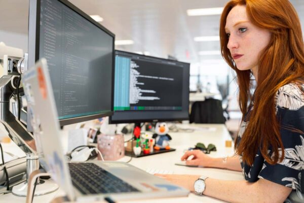 Woman Web Developer working on Two Screens