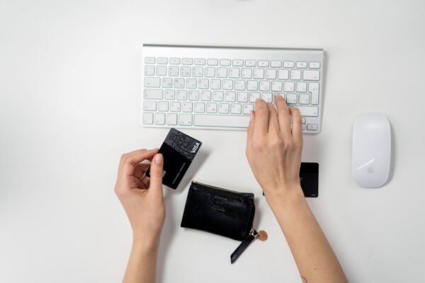 Person Typing On A Keyboard While Holding A Visa Card