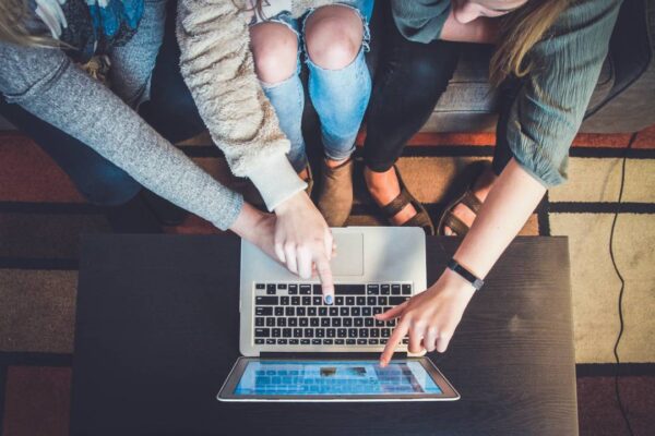 Three Women Pointing at A Laptop Screen